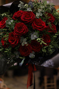 Bouquet of red roses with greenery on a dark background