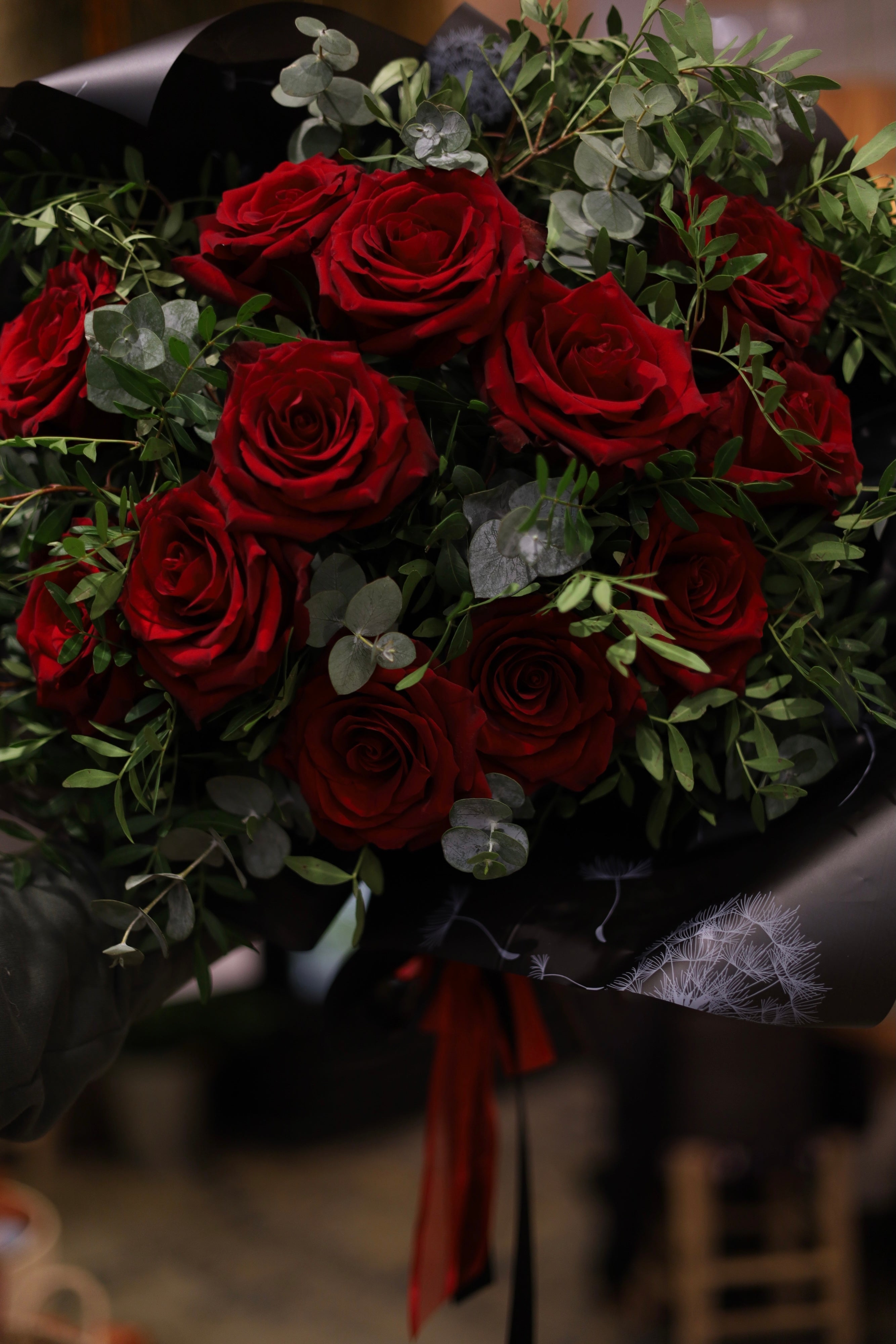 Bouquet of red roses with greenery on a dark background